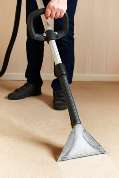 This is a photo of a man steam cleaning a cream carpet, using a professional steam cleaning machine works carried out by Haggerston Carpet Cleaning