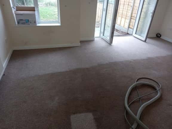 This is a photo of an empty living room with a brown carpet that is in the process of having its carpets steam cleaned works carried out by Haggerston Carpet Cleaning