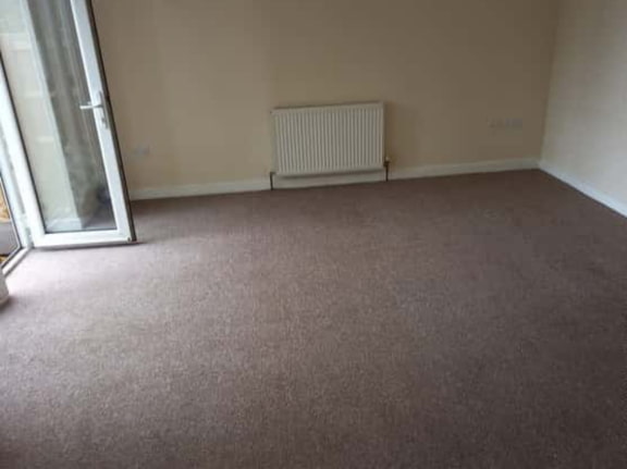 This is a photo of a living room after it has been cleaned. The room is empty and has a brown carpet that has been steam cleaned works carried out by Haggerston Carpet Cleaning