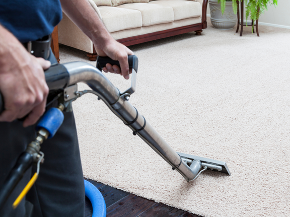 This is a photo of a man with a steam cleaner cleaning a cream carpet works carried out by Haggerston Carpet Cleaning